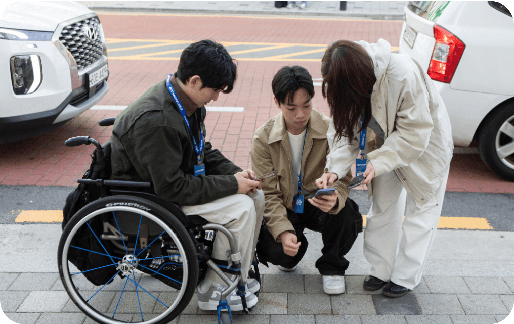 휠체어 사용자와 친구들이 함께 휴대폰을 보는 모습